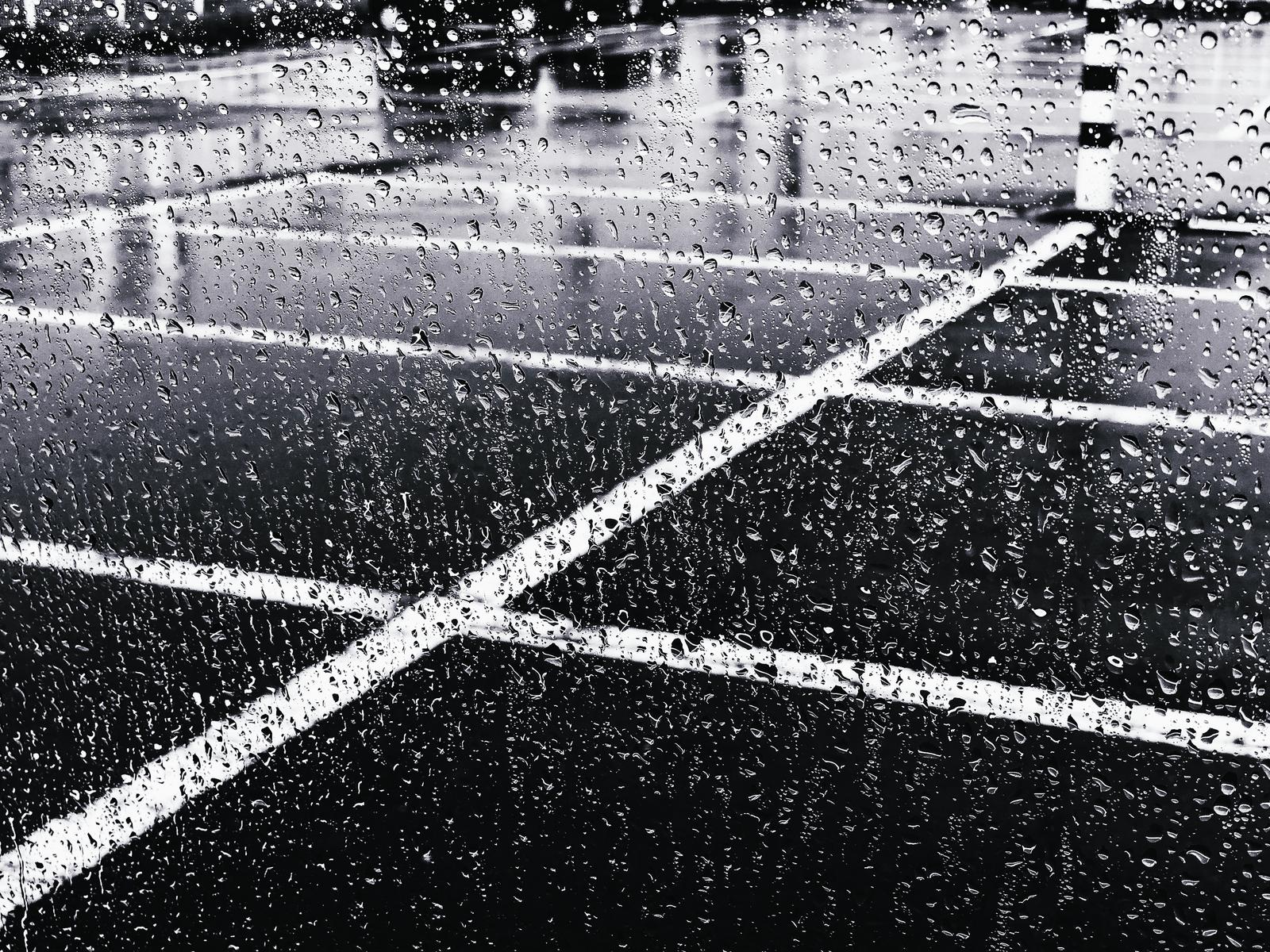 大雨でフロントガラスに付いた水滴と、ぼやけた背景の風景
