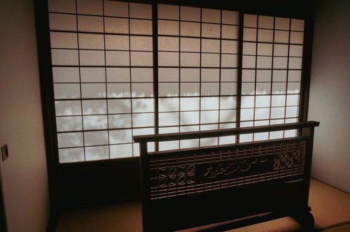 黒い欄間彫刻と障子が特徴の和室の畳張り空間