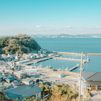 青空の下、山と海に囲まれた塩津漁港の風景の写真