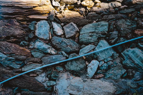 青いロープが横切る風化した石垣のテクスチャー