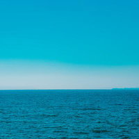 遠くに霞む島影と広がる青い海の水平線の写真