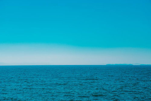 遠くに霞む島影と広がる青い海の水平線