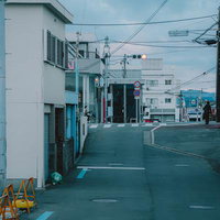 紀三井寺の坂道の先に灯る赤信号と白い建物の町並みの写真