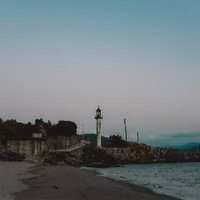 和歌浦から見える灯台と夕暮れの海岸風景、岩場と防波堤の写真