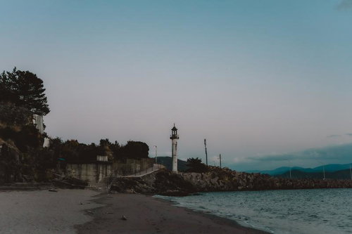 和歌浦から見える灯台と夕暮れの海岸風景、岩場と防波堤