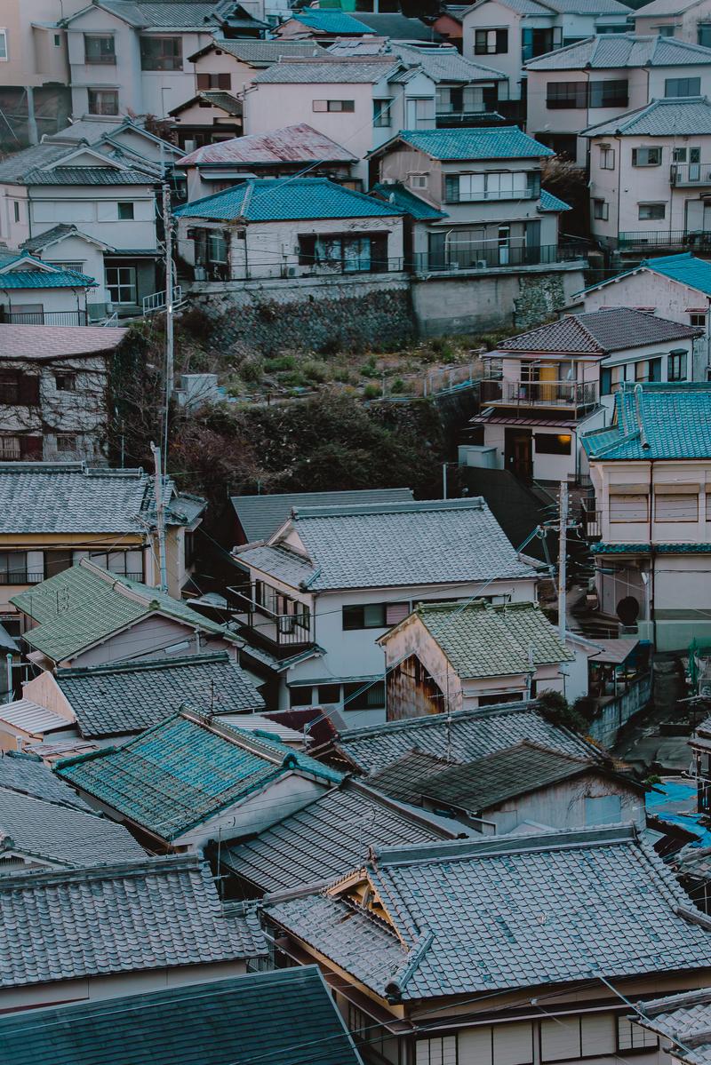 斜面に密集して建つ瓦屋根の日本家屋が上下に重なるように立ち並ぶ景観