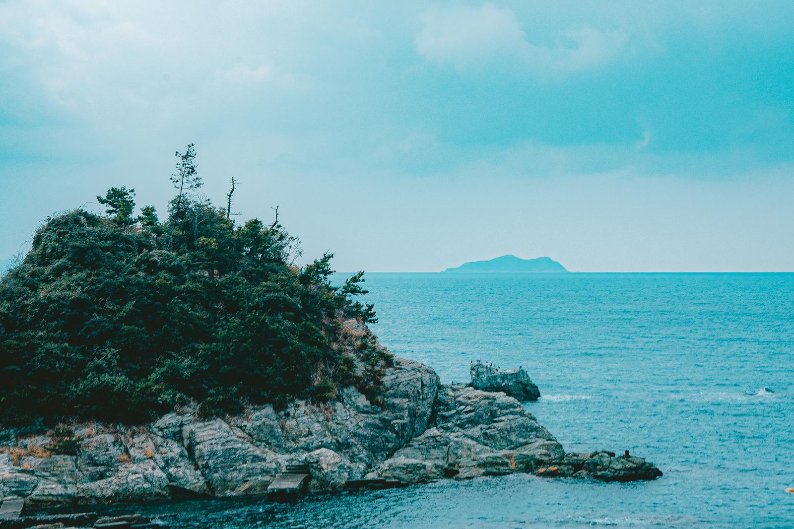 緑の樹木が茂る岩場の小島と遠くに見える島