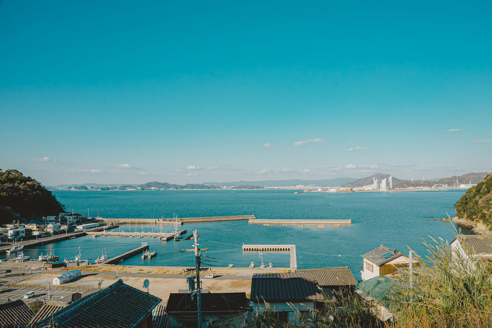 塩津漁港の漁船と防波堤がある港湾風景と遠くの都市景観