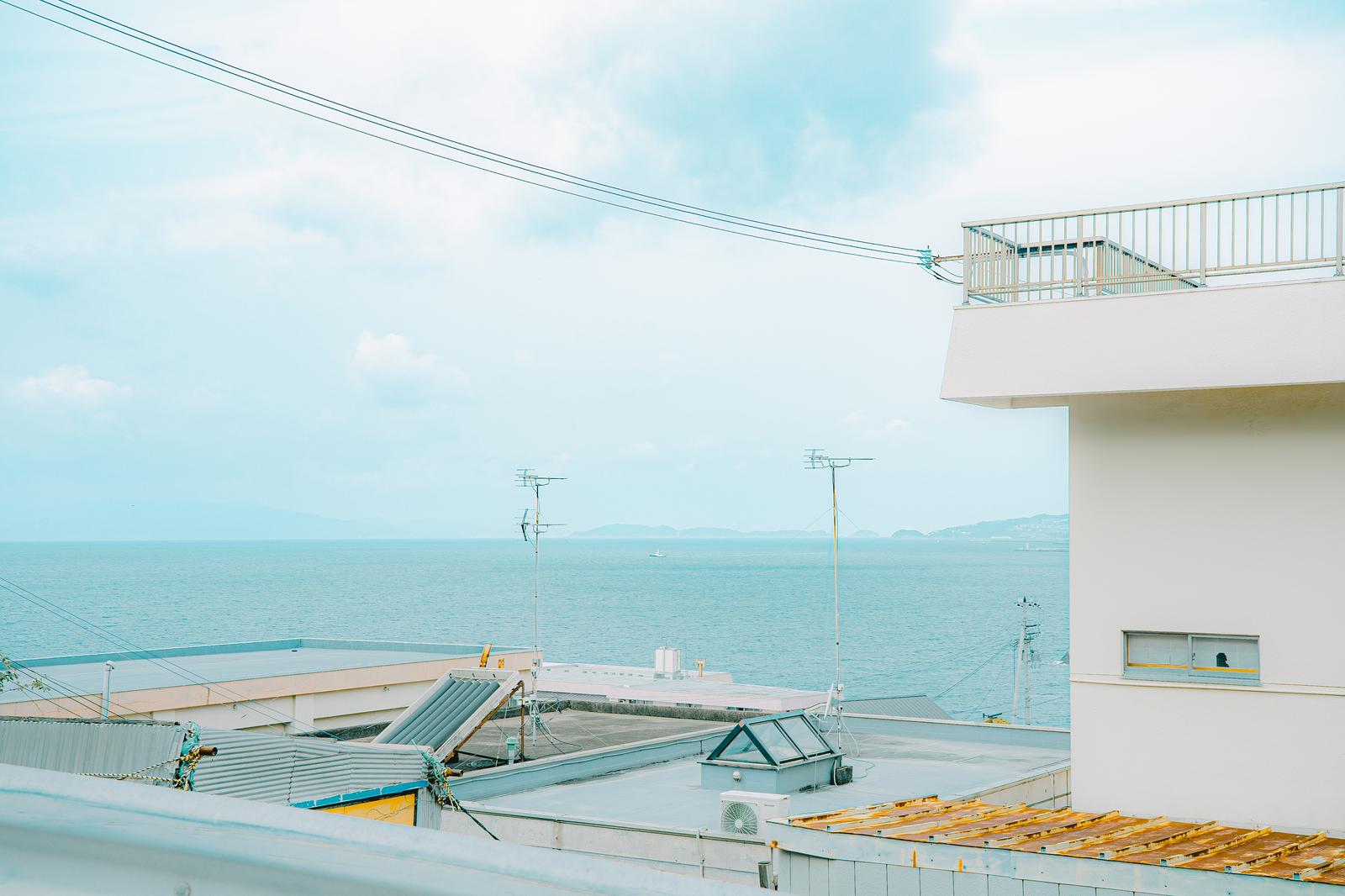 高台から海へ向かうガードレール越しに見た雑賀崎の港町風景
