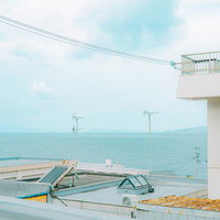 高台から望む雑賀崎の港町と水平線、ガードレール越しの海景の写真
