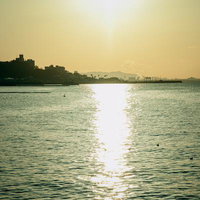 沈みゆく夕陽が水面に光の道を描く港町の風景の写真