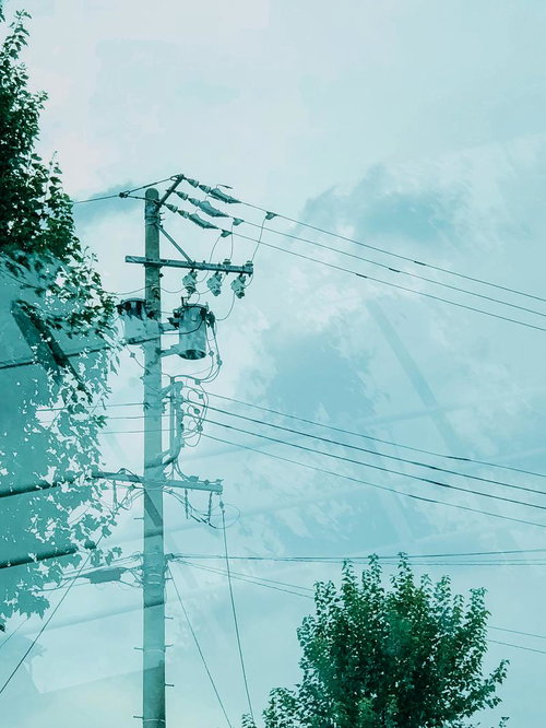 ガラスに反射する電信柱と複数の電線がある都市風景