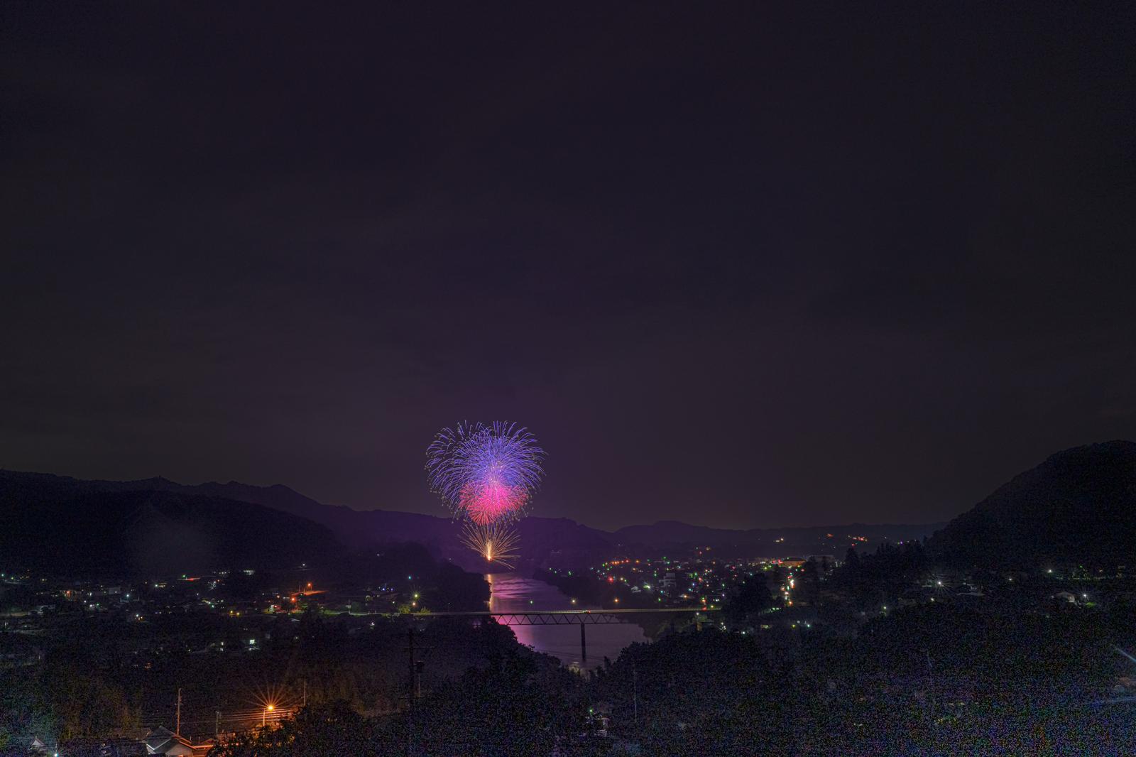 八百津町花火大会で夜空に打ち上がるピンク色の花火と町並みの夜景