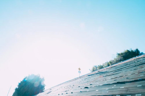 さわやかな青空と新緑の堤防、測量標識が立つ風景