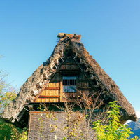 合掌造りの茅葺き屋根と木製の階段窓・富山県南砺市の伝統民家の写真