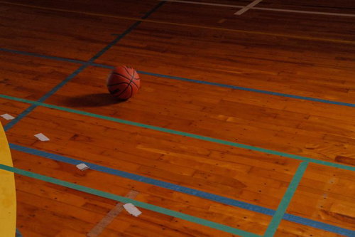 体育館のウッドフロアに転がるバスケットボール