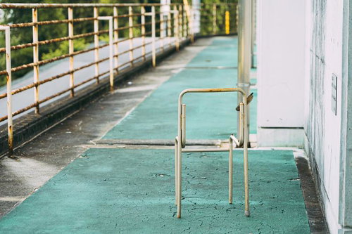 緑色の通路に放置された錆びた金属椅子の支柱