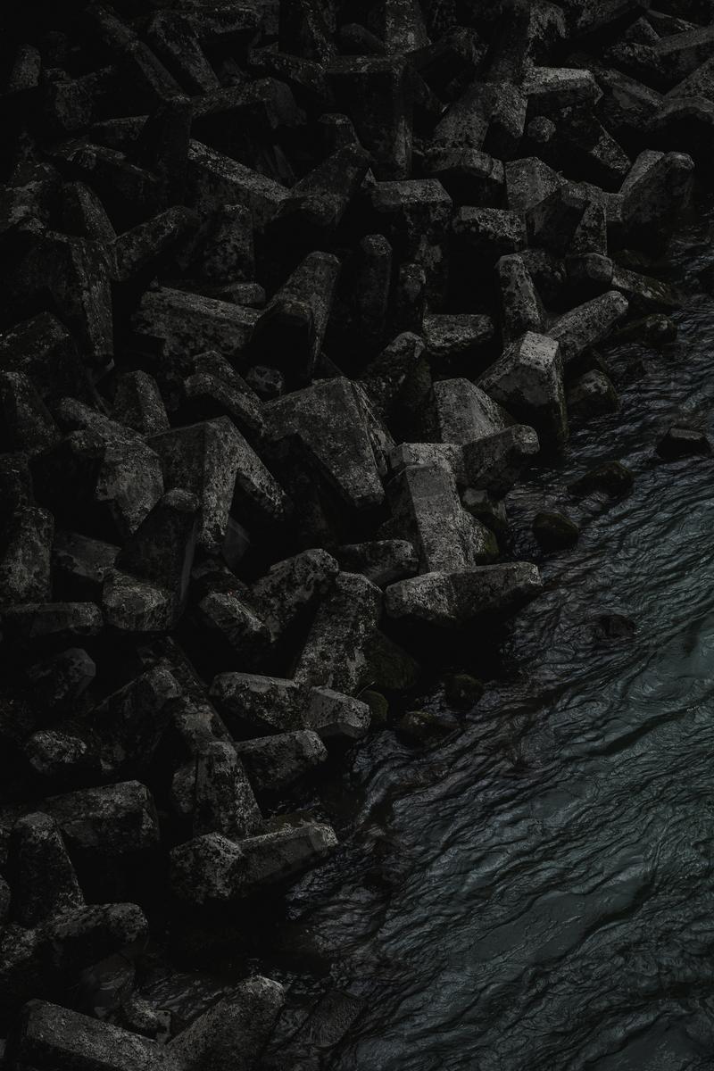 積み重なったテトラポッドの波消しブロック。奥に水面が見える