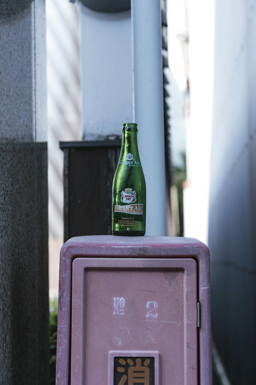 都会の路地に置かれたジンジャーエールの空き瓶
