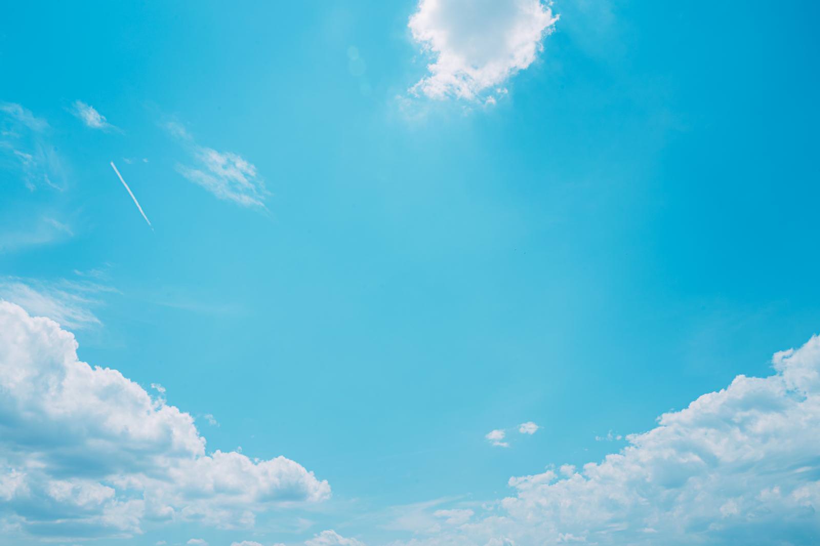 快晴の青空に白い積雲と飛行機雲が浮かぶ風景