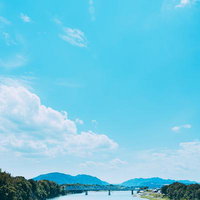 青空と白い雲が流れる川と橋の自然風景の写真