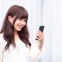 新しいスマートフォンの高色域ディスプレイを見つめて笑顔のキラキラ女性の写真