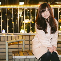 繁華街のイルミネーション前で待ち合わせする女性の写真