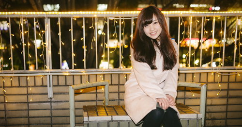 繁華街のイルミネーション前で待ち合わせする女性