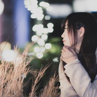 夜景の玉ボケの中、進路について真剣に悩む女子大生の写真