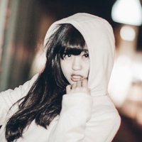 フード姿で指を頬に当てるおかぶり女子の夜間ポートレートの写真