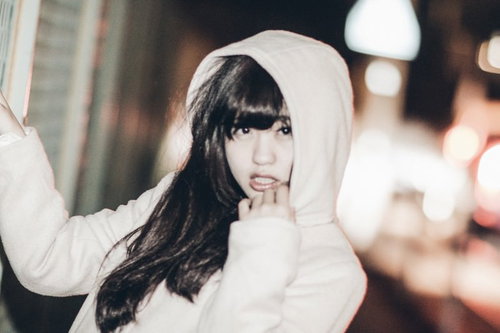 フード姿で指を頬に当てるおかぶり女子の夜間ポートレート