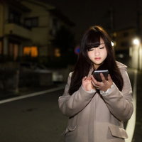 深夜に歩きスマホをする女の子の危険な一人歩きの写真