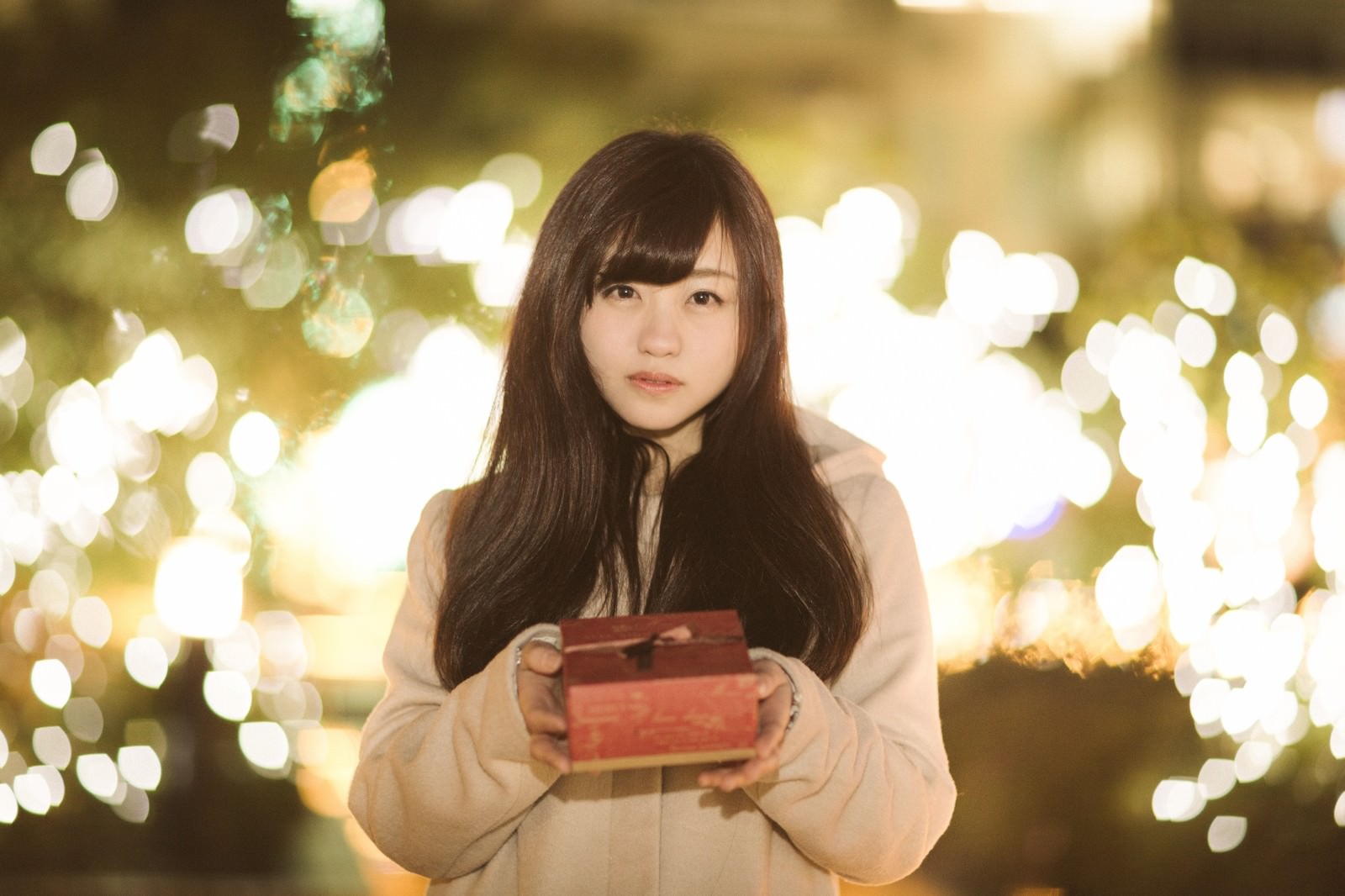 イルミネーション前でプレゼントを抱える女性［モデル：河村友歌］