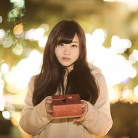 イルミネーション前、プレゼントを抱えて勇気を出す女性の写真