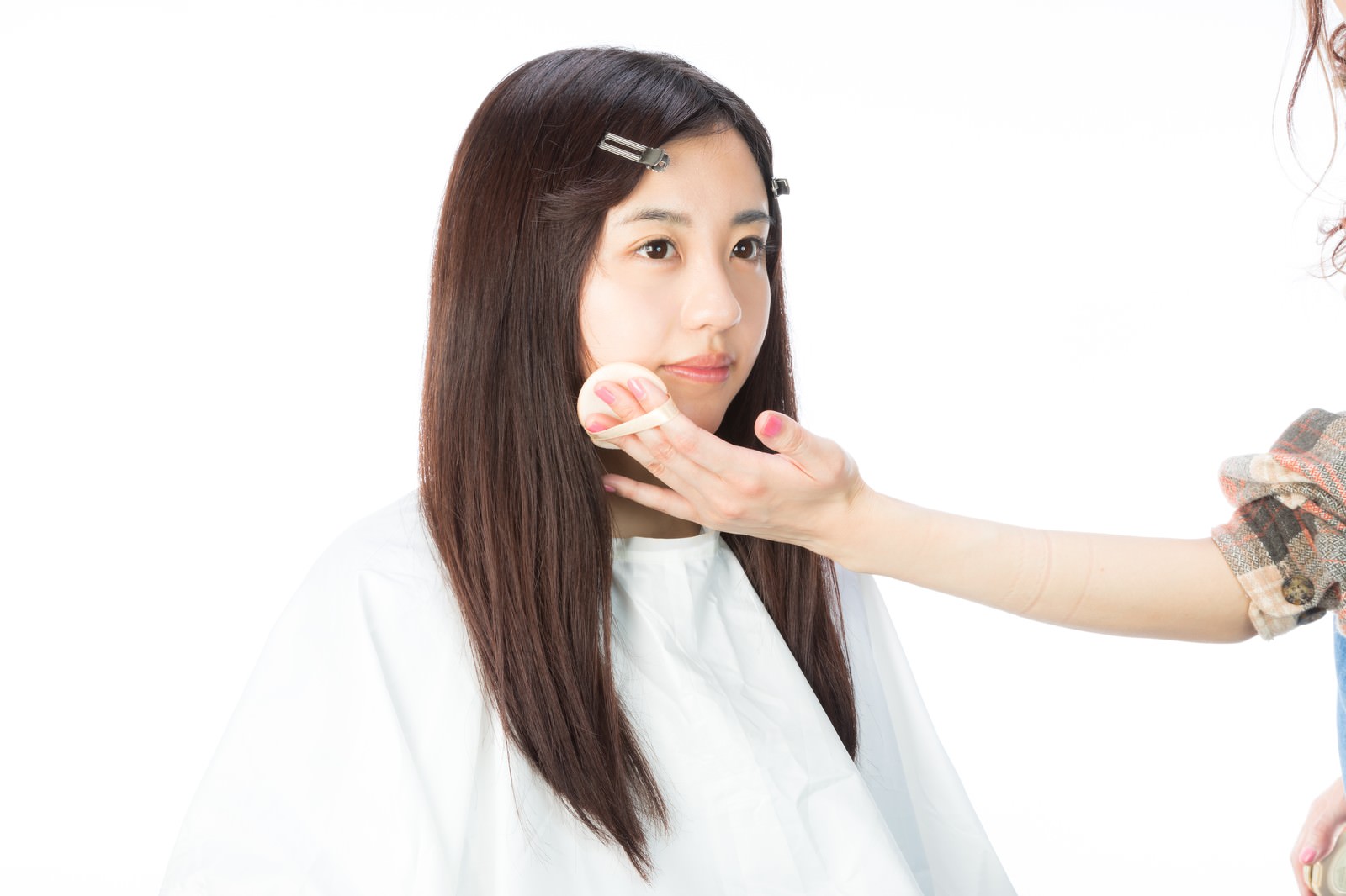白いガウンを着た女性がファンデーションを塗ってもらっている［モデル：河村友歌］