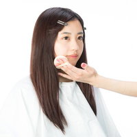 ファンデーションを塗られるメイク中の女性の写真