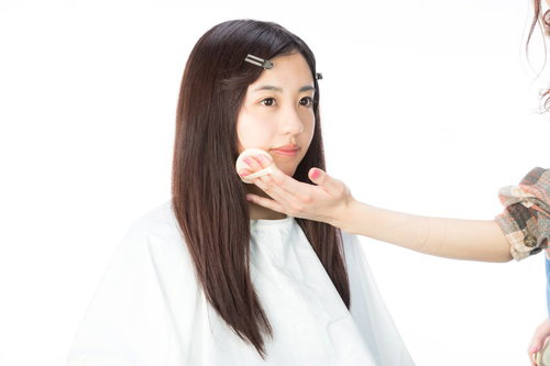 ファンデーションを塗られるメイク中の女性