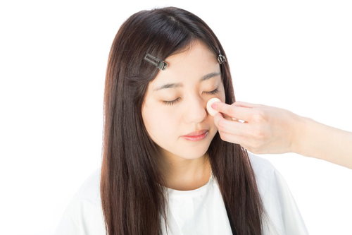 ベースメイク中の白い服の女性がファンデーションを塗布