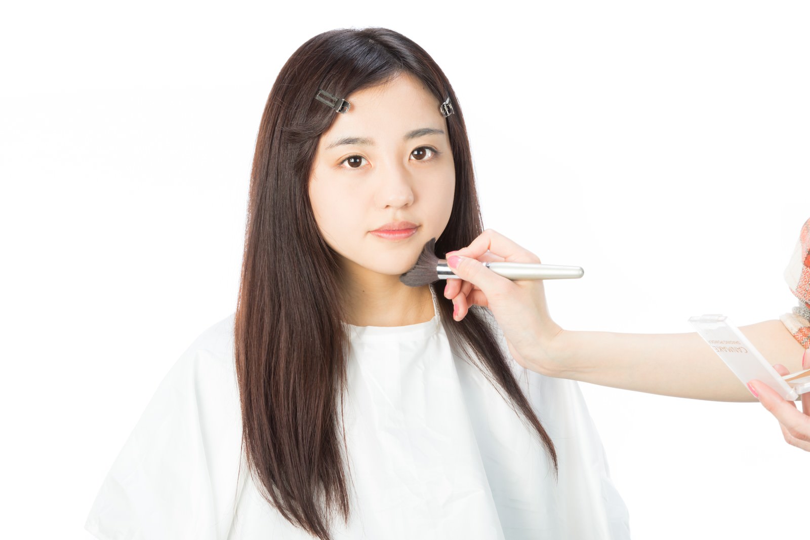 白い背景でメイクブラシを使ってフェイスシャドウを入れる女性［モデル：河村友歌］