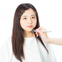 メイクブラシでフェイスシャドウを入れる女性の写真