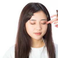 アイシャドウを指でなじませるメイク中の女性の写真