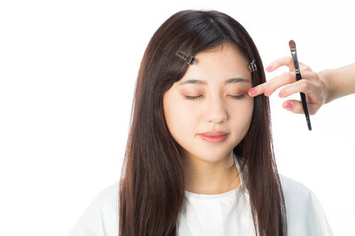 アイシャドウを指でなじませるメイク中の女性