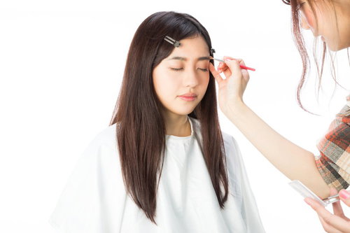 メイクアップアーティストに眉毛を描いてもらう女性
