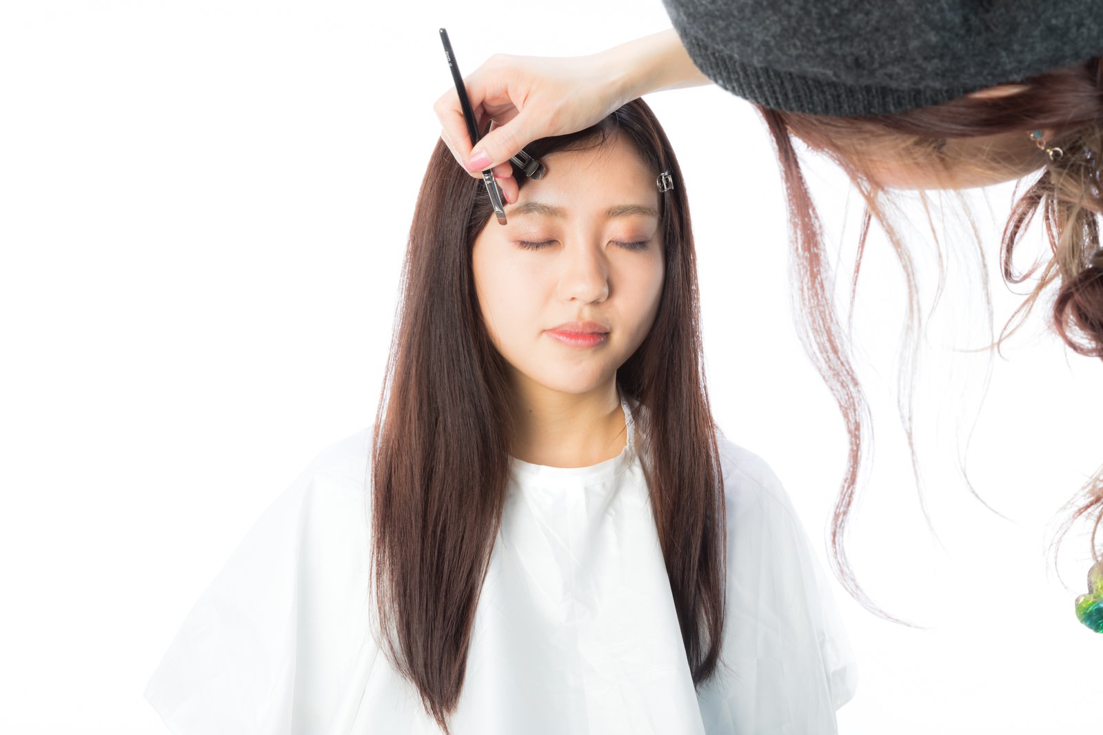美容師が女性にアイラインを引いているメイク施術の様子［モデル：河村友歌］