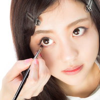 メイクブラシで下瞼にアイシャドウを入れる女性の写真