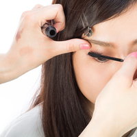 まつ毛にマスカラを丁寧に塗る女性のメイク過程の写真