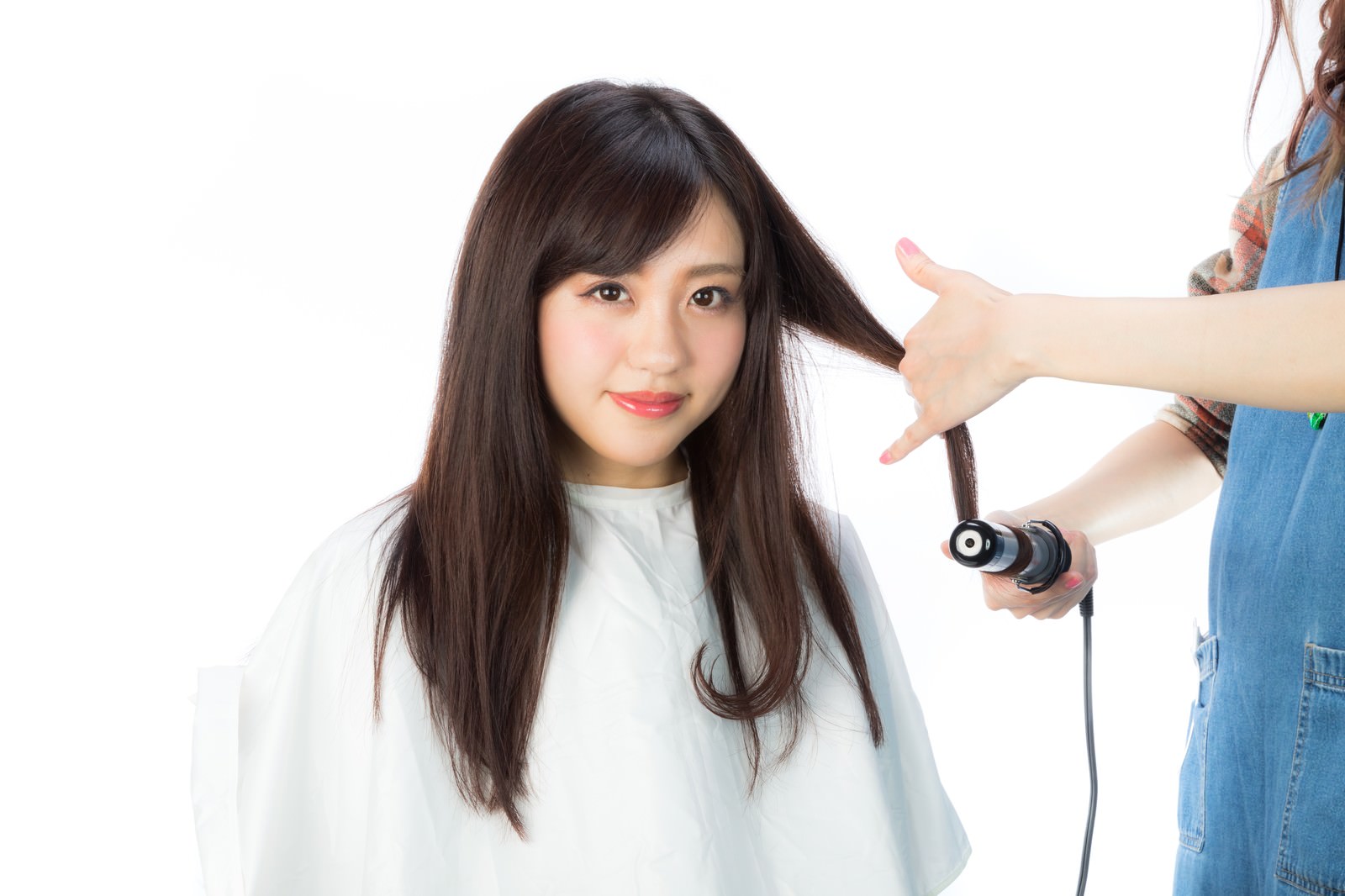 美容院でヘアアイロンを使って髪を巻く女性［モデル：河村友歌］