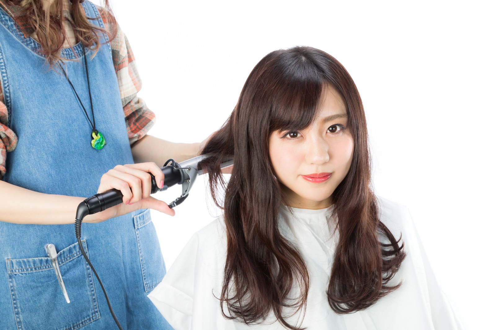 ヘアアイロンで女性の後ろ髪を巻く美容師の手元［モデル：河村友歌］