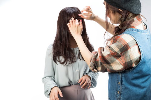 撮影現場でモデルのヘアメイクを手直しする美容師