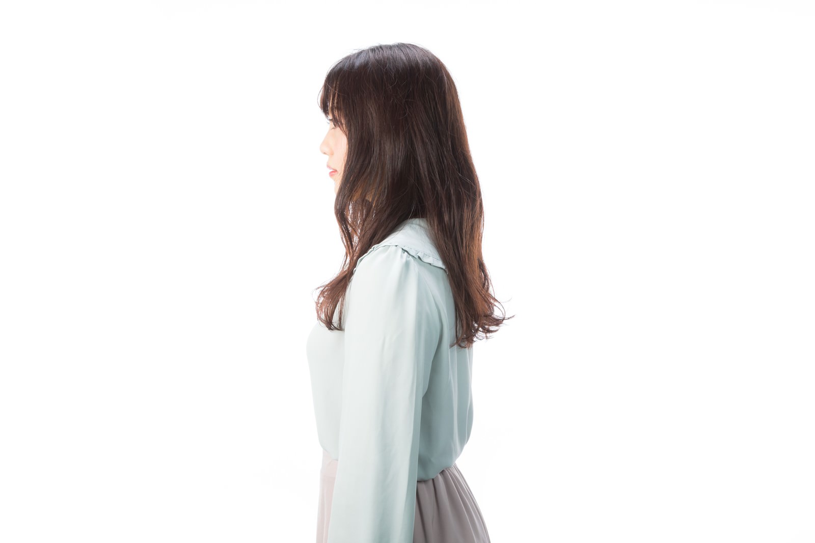 白い背景の前で横を向くロングヘアの女性のポートレート［モデル：河村友歌］